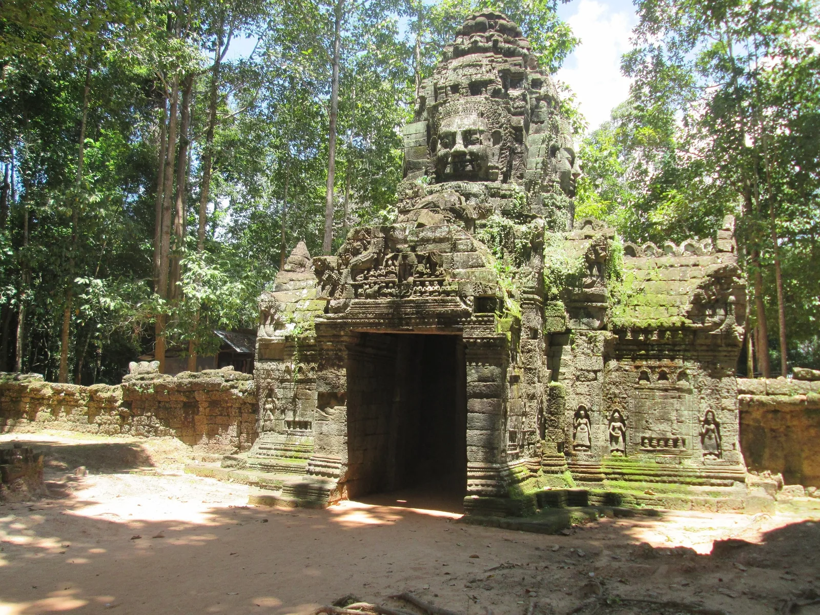A stone gate tower carved with a giant face marks the entrance to Ta Som temple, surrounded by jungle in Siem Reap.