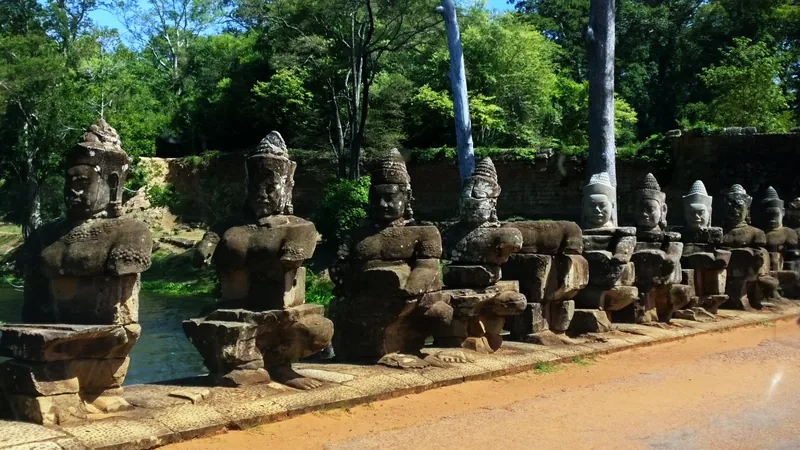 A row of ancient stone statues lines the causeway bridge at Angkor Thom near Siem Reap, Cambodia.