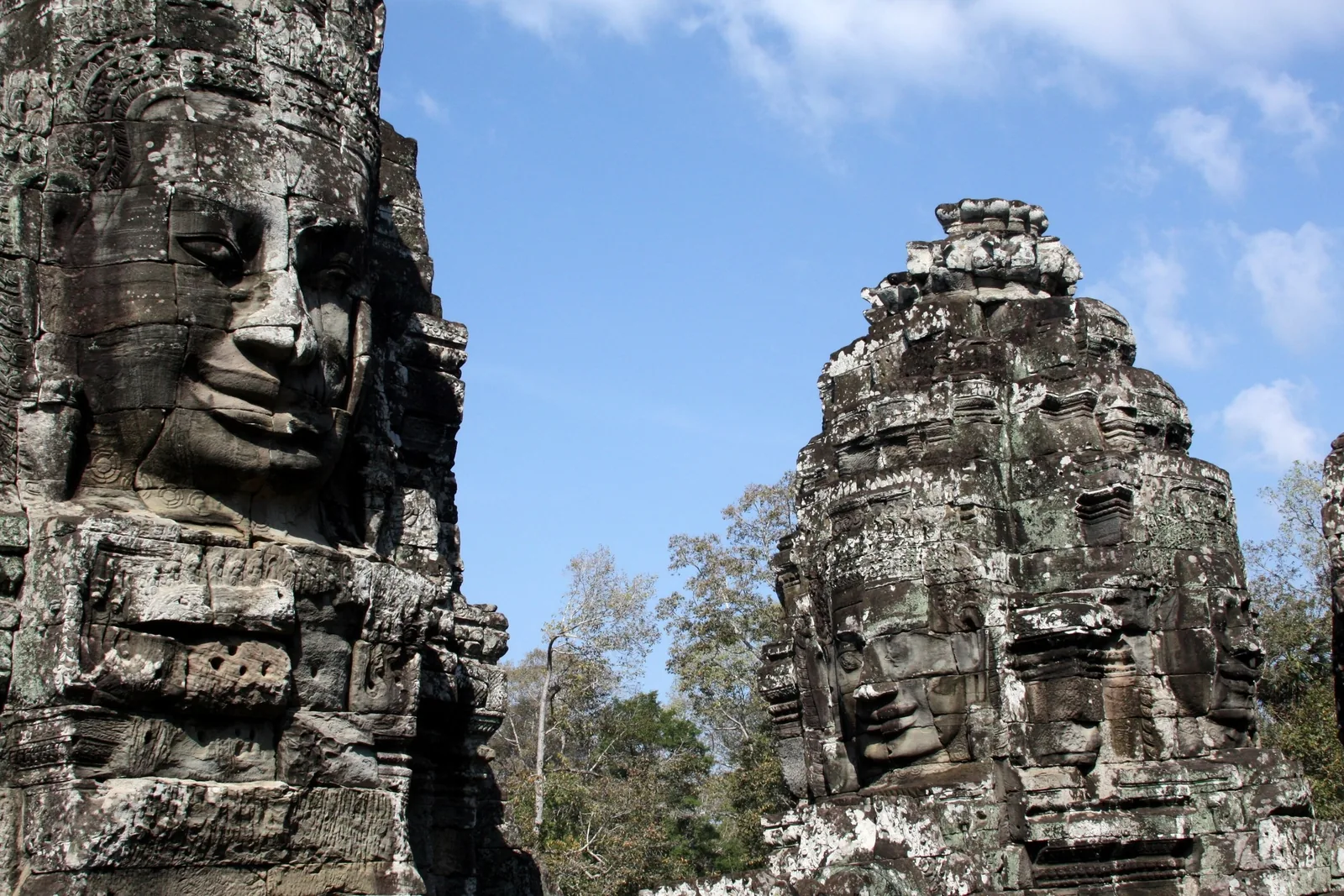 Stone face towers of Bayon temple rise against a blue sky in Siem Reap, Cambodia.