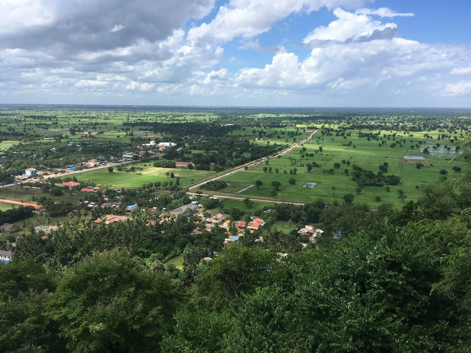 Aerial view from Phnom Sampeau overlooking a patchwork of green rice fields and village rooftops near Battambang.