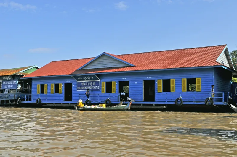 A blue floating school building with a red roof sits on the murky waters of Tonle Sap near Siem Reap.