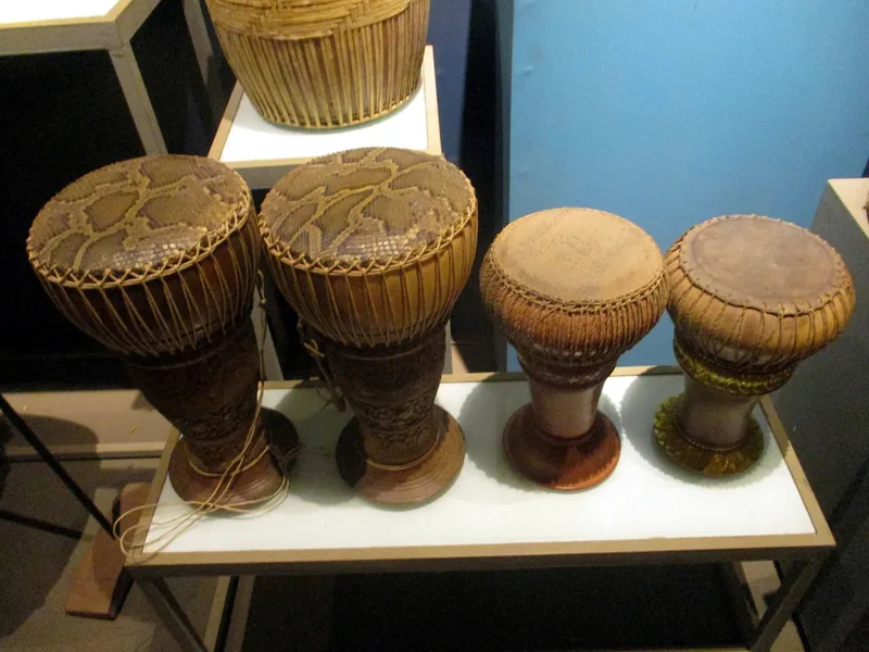Traditional goblet-shaped skor daey drums with snakeskin and hide heads displayed in a museum exhibit in Siem Reap.