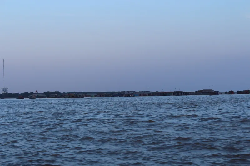 Floating houses line the horizon on Tonle Sap Lake near Siem Reap at dusk.