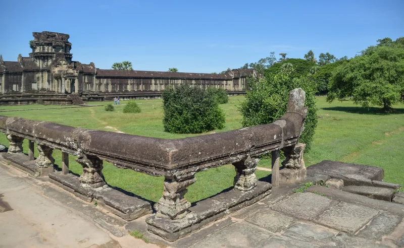 A naga-headed stone balustrade leads toward the outer galleries and tower of Angkor Wat in Siem Reap.