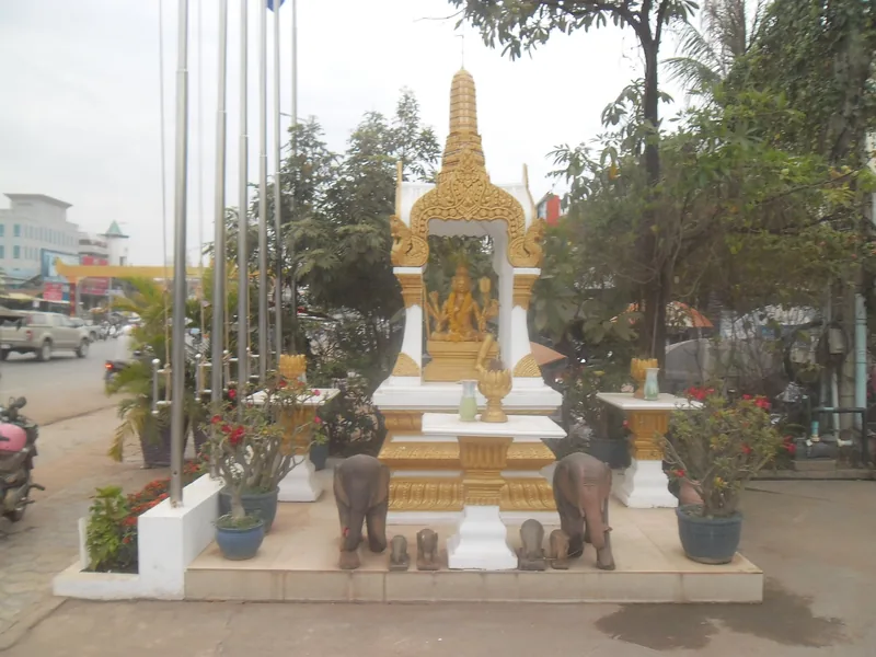A small golden spirit shrine with elephant statues stands along a street in Siem Reap, Cambodia.