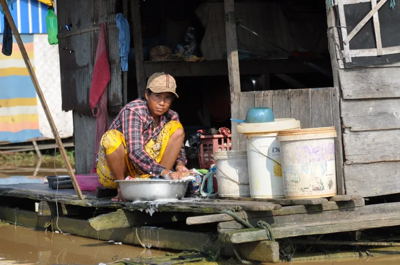 A woman washes clothes in a metal basin outside her wooden floating house on Tonle Sap lake near Siem Reap.