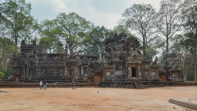 Weathered stone towers and galleries of a Khmer temple stand amid trees near Siem Reap, Cambodia.
