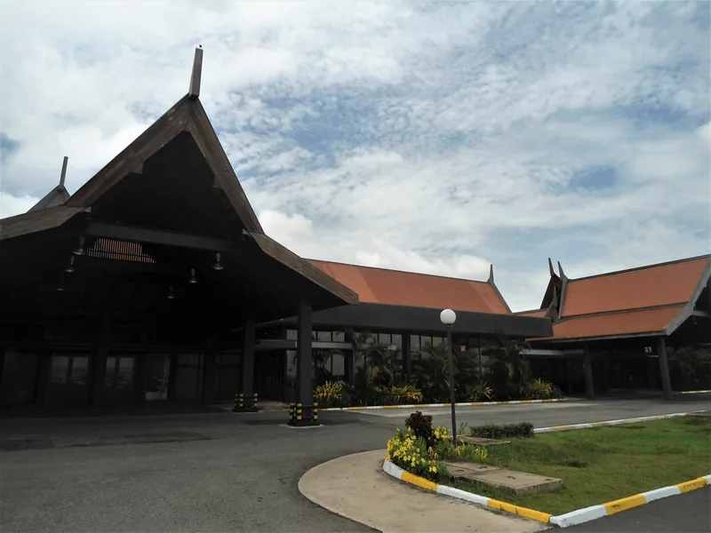 Traditional Khmer-style peaked roofs cover the terminal building at Siem Reap International Airport under a cloudy sky.