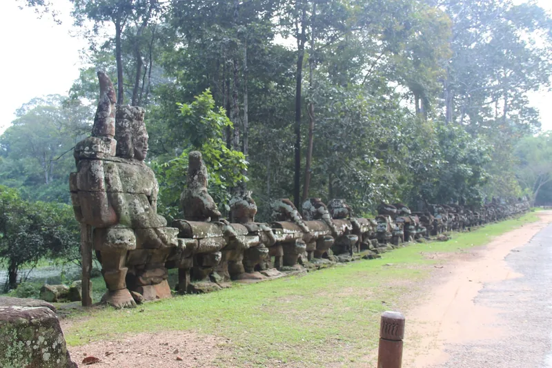 Weathered stone figures line the causeway leading to the Victory Gate of Angkor Thom in Siem Reap.