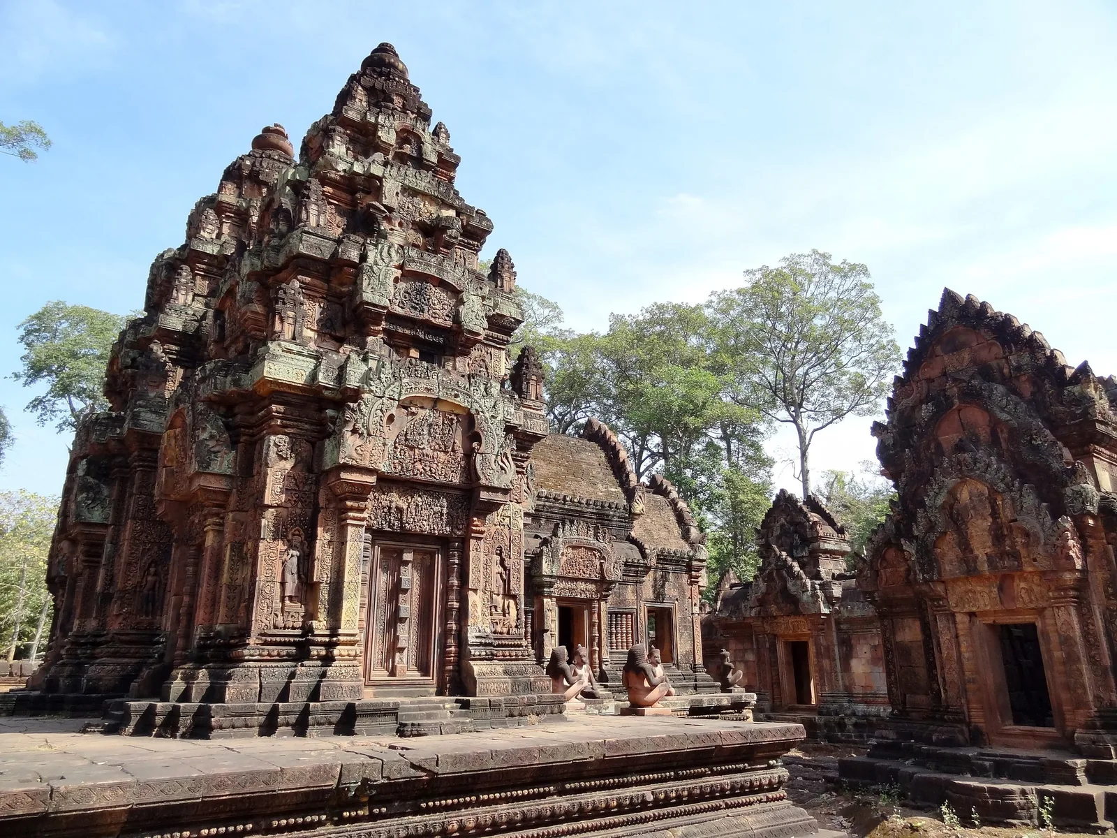 Intricately carved pink sandstone towers of Banteay Srei temple stand under a clear sky near Siem Reap.