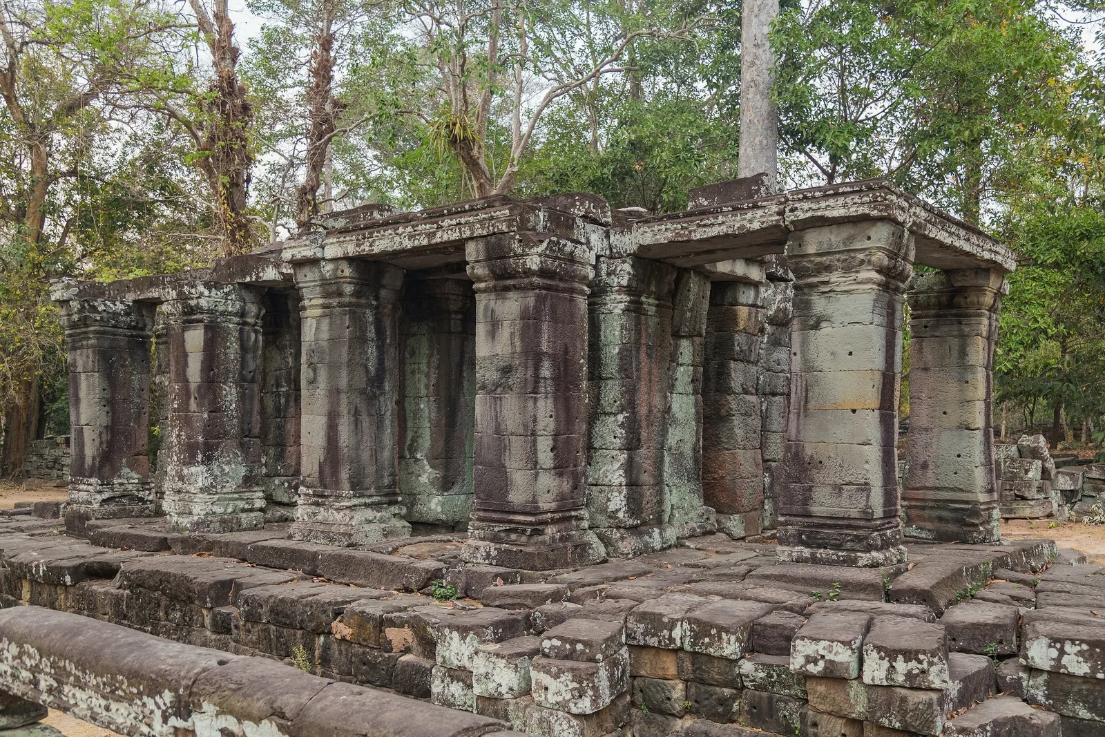 Weathered stone columns and gallery ruins stand among trees at Banteay Kdei temple in Siem Reap, Cambodia. Weathered stone columns and gallery ruins stand among trees at Banteay Kdei temple in Siem Reap, Cambodia.