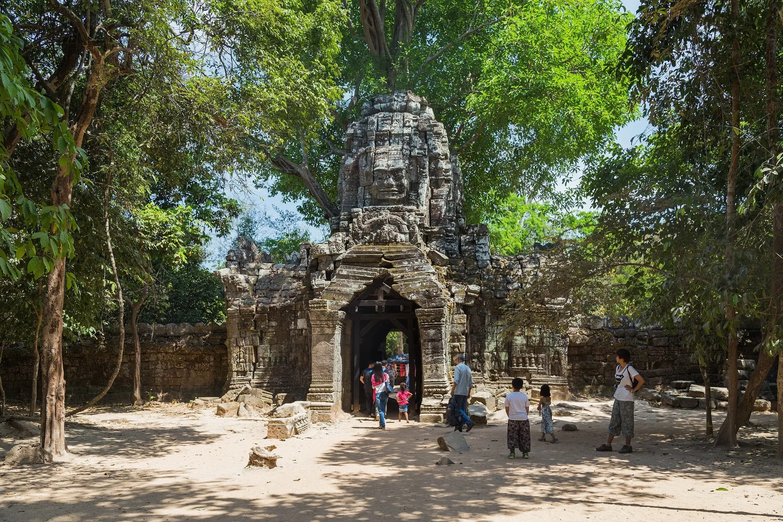 Visitors gather at the stone gate tower carved with a giant face at Ta Som temple near Siem Reap, Angkor.