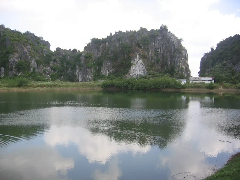 Limestone karst hills rise above a still lake near Kampong Trach in Kampot province, Cambodia.