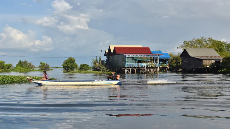 A long-tail boat speeds past stilt houses on the water at Kampong Khleang near Siem Reap.