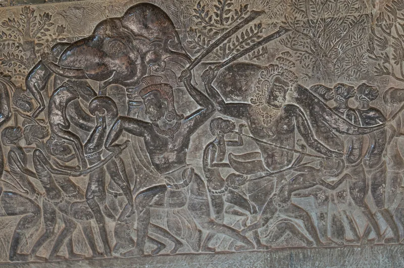 A stone bas-relief carving of warriors and elephants adorns a temple wall at Angkor Wat, Siem Reap.