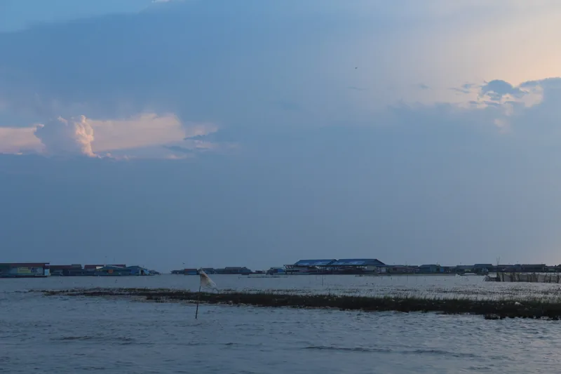 Floating houses line the horizon on Tonle Sap Lake near Siem Reap under a soft evening sky.