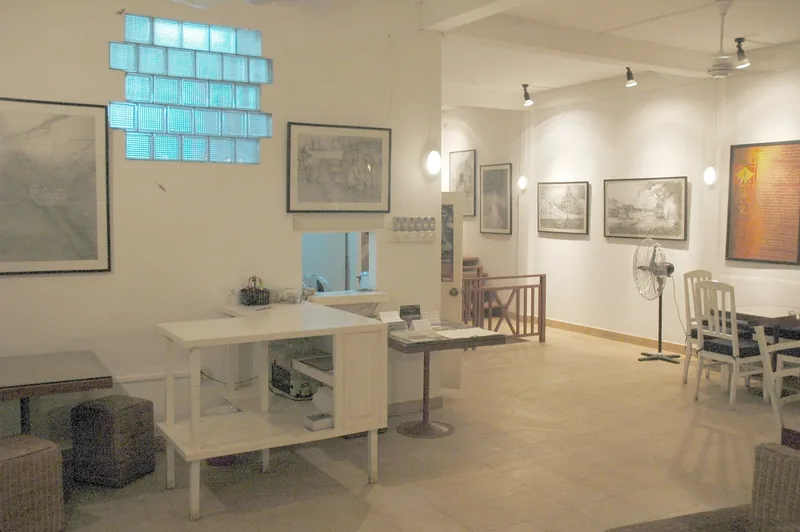 An art gallery interior in Siem Reap displays framed sketches and paintings along white walls beside a seating area.
