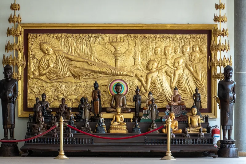A gilded relief depicting the reclining Buddha towers over rows of Buddha statues at the Royal Palace in Phnom Penh.