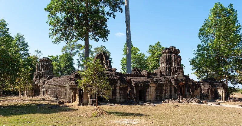 Ancient stone ruins of Banteay Prei temple stand amid tall trees near Siem Reap, Cambodia.