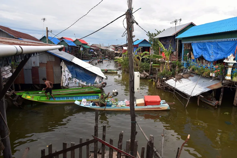 Boats navigate a flooded street between stilt houses in the floating village of Kampong Khleang near Siem Reap.