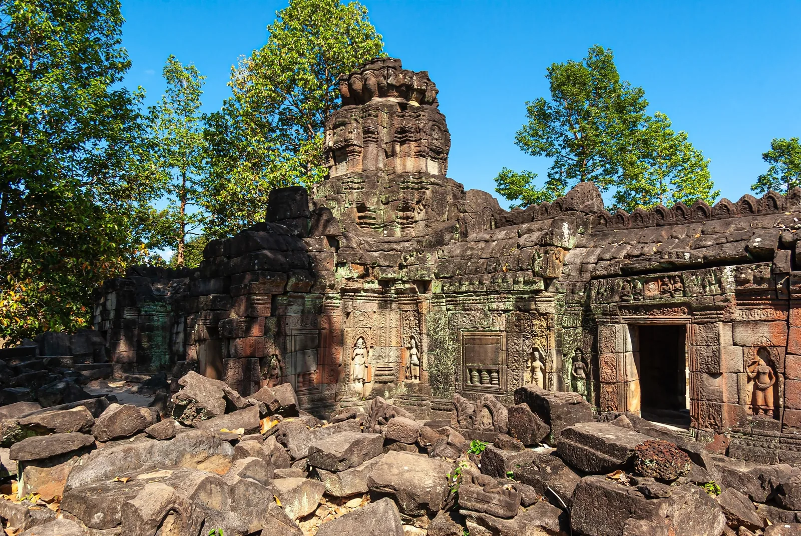 Weathered stone tower and carved reliefs at Banteay Prei temple ruins near Siem Reap, surrounded by scattered rocks and.